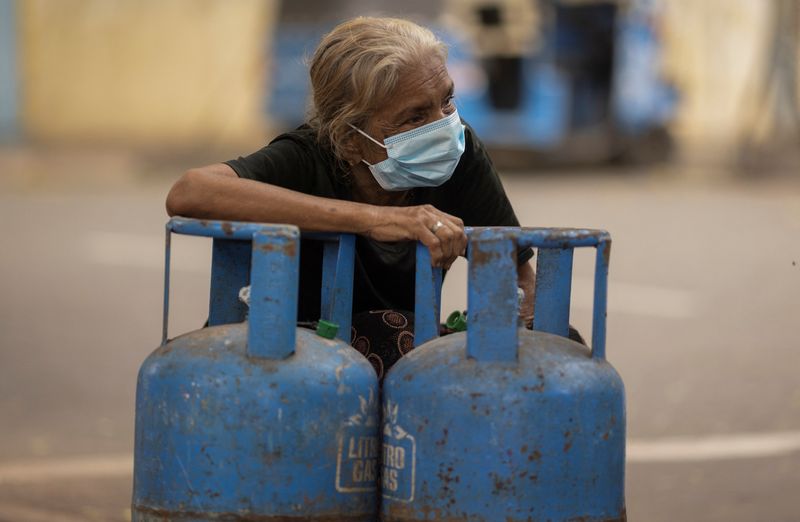 &copy; Reuters. FILE PHOTO: A woman sits next to her filled domestic cooking gas cylinder after its distribution, amid the country's economic crisis, in Colombo, Sri Lanka, July 23, 2022. REUTERS/Adnan Abidi