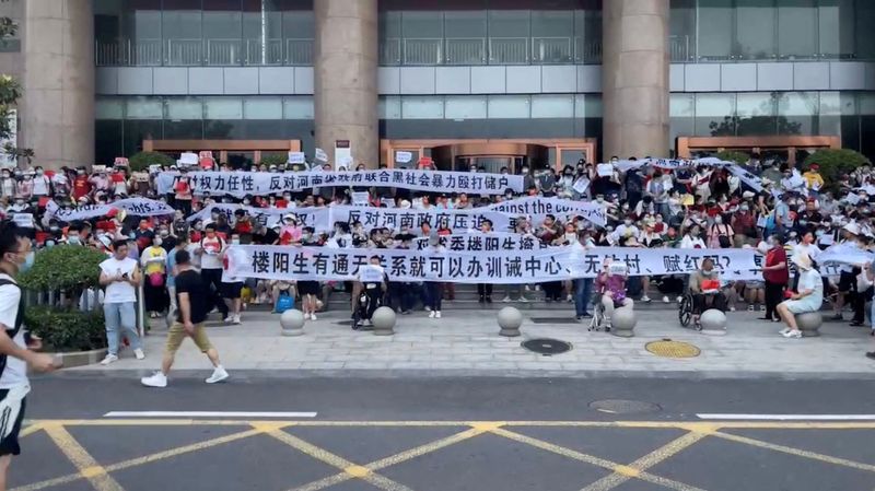 &copy; Reuters. Demonstrators hold banners during a protest over the freezing of deposits by rural-based banks, outside a People's Bank of China building in Zhengzhou, Henan province, China July 10, 2022, in this screengrab taken from video obtained by Reuters.