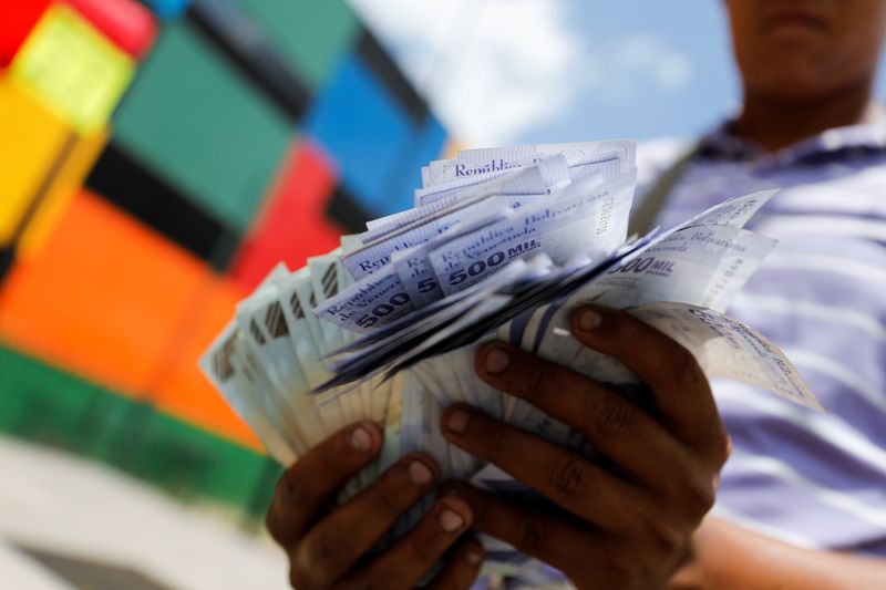 &copy; Reuters. Imagen de archivo del ayudante de un conductor de autobús sosteniendo billetes de 500.000 bolívares, cada uno con un valor de apenas 0,12 dólares, después de que el banco central de Venezuela anunció que recortará seis ceros de los precios, en Carac