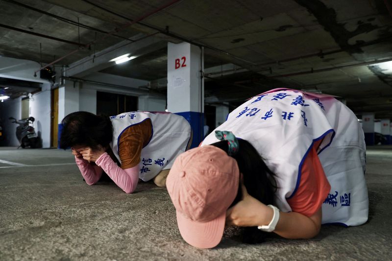 &copy; Reuters. FILE PHOTO: People demonstrate taking shelter with their hands covering their eyes and ears while keeping their mouth open, during a drill at a basement parking lot that will be used as an air-raid shelter in the event of an attack, in Taipei, Taiwan, Jul