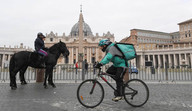 &copy; Reuters. A food delivery employee rides a bike near police officers on horses next to the St. Peter's Square, on the fourth day of an unprecedented lockdown across of all Italy imposed to slow the outbreak of coronavirus, in Rome, Italy, March 13, 2020. REUTERS/Al