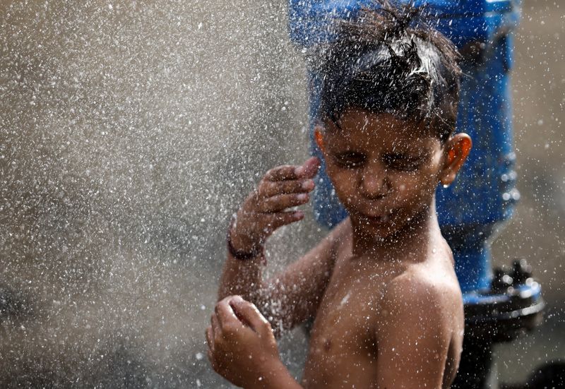 &copy; Reuters. طفل يبرد نفسه بماء أنبوب مكسور في نيودلهي يوم 17 مايو أيار 2022. تصوير: أنشوري فادنافيس - رويترز