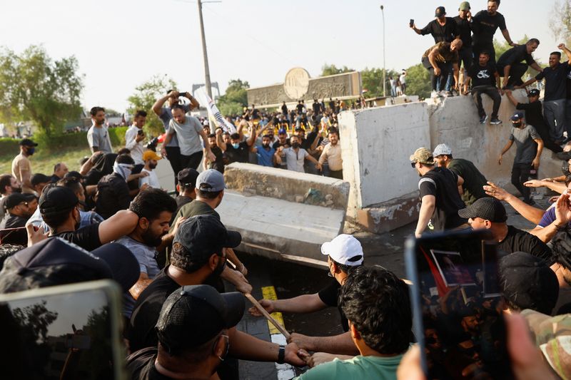 &copy; Reuters. متظاهرون من أنصار التيار التنسيقي الموالي للشيعة يسقطون حواجز خرسانية في أحد شوارع العاصمة العراقية بغداد خلال مظاهرة في الأول من أغسطس 2022.