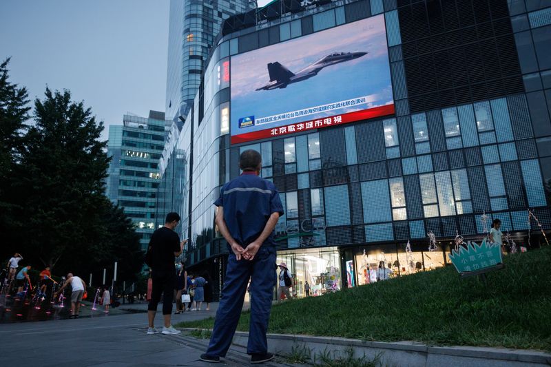 &copy; Reuters. أحد المارة يشاهد بثا على شاشة في أحد شوارع بكين لطلعة عسكرية صينية قرب تايوان يوم الأربعاء. تصوير توماس بيتر- رويترز.