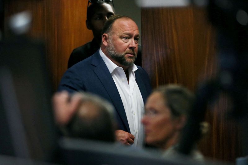 © Reuters. FILE PHOTO: Alex Jones walks into the courtroom in front of Scarlett Lewis and Neil Heslin, the parents of 6-year-old Sand Hook shooting victim Jesse Lewis, at the Travis County Courthouse in Austin, Texas, U.S. July 28, 2022. Briana Sanchez/Pool via REUTERS