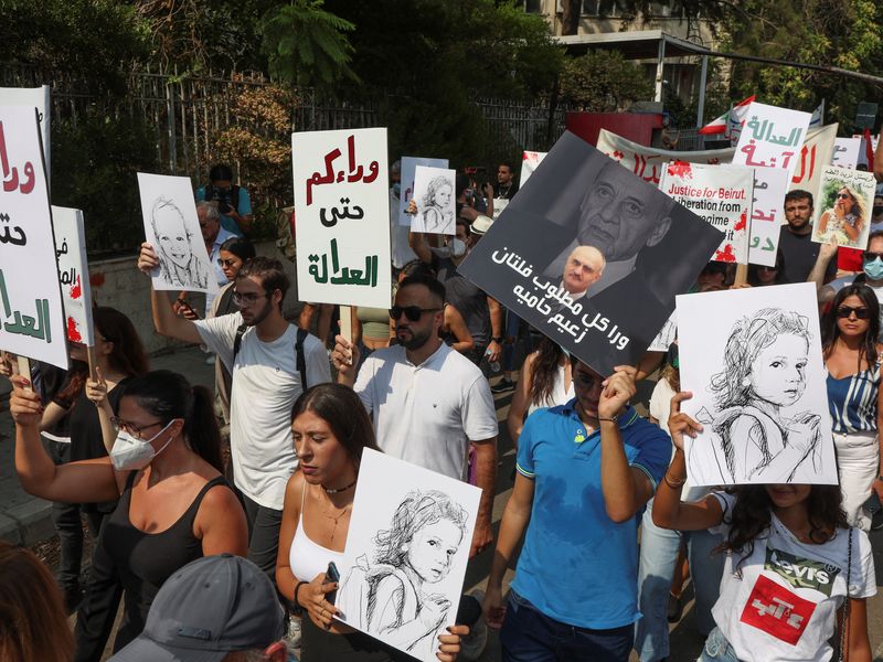 © Reuters. أشخاص يحملون لافتات خلال احتجاجات في الذكرى الثانية لانفجار مرفأ بيروت يوم الخميس. تصوير: محمد عزاقير-رويترز يحظر اعادة بيع هذه الصورة أو الاحتفاظ بها في أرشيف.