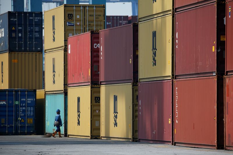 © Reuters. FILE PHOTO: A worker carrying a broom passes stacks of containers at the IPC Containter Terminal of Tanjung Priok port in Jakarta, Indonesia, November 4, 2021. REUTERS/Willy Kurniawan