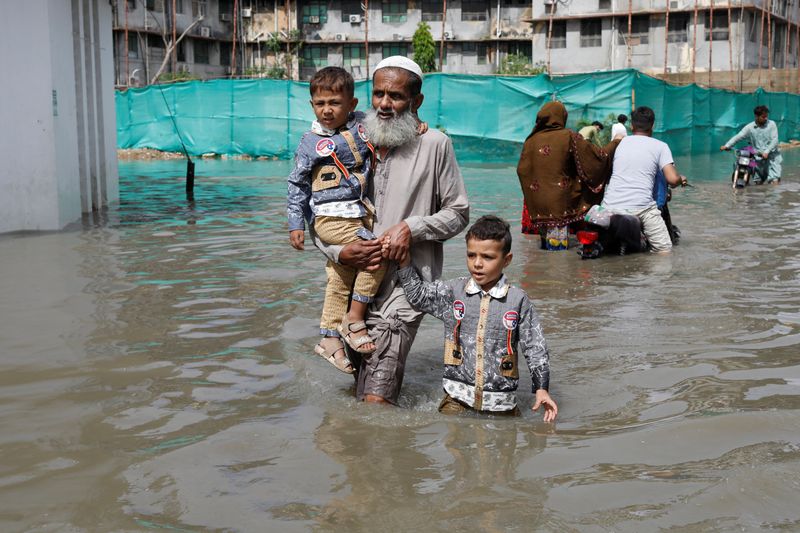 &copy; Reuters. سكان يسيرون وسط شارع غمرته مياه الفيضانات في كراتشي بباكستان في 11 يوليو تموز 2022. تصوير : أختار سومرو- رويترز . 