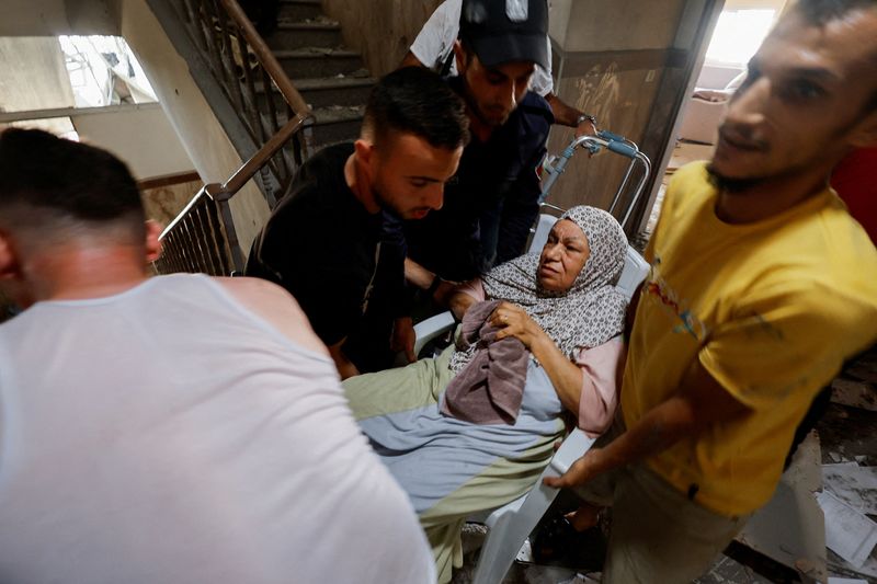 &copy; Reuters. عاملون في خدمات الطوارئ يقومون بإجلاء امرأة مسنة من منزل بعد ضربة إسرائيلية في غزة يوم الجمعة. تصوير: محمد سالم - رويترز. 