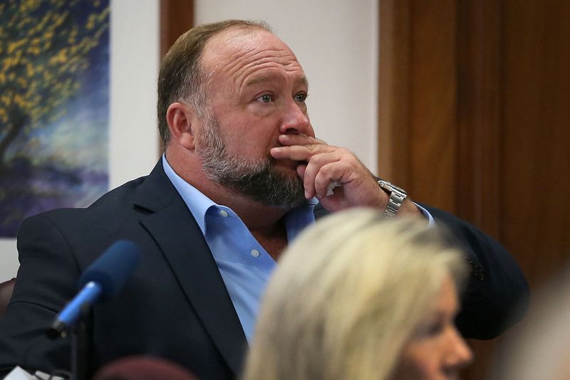 © Reuters. Alex Jones attempts to answer questions about his text messages asked by Mark Bankston, lawyer for Neil Heslin and Scarlett Lewis, during trial at the Travis County Courthouse , Austin, Texas, U.S., August 3, 2022.  Briana Sanchez/Pool via REUTERS