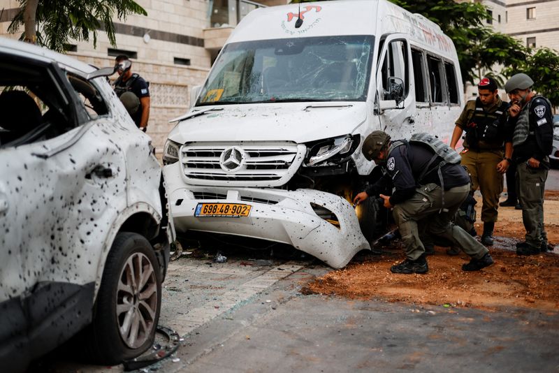 © Reuters. أفراد من الشرطة الإسرائيلية يفحصون حافلة تضررت في أعقاب الهجوم بصواريخ من غزة باتجاه عسقلان يوم السبت. تصوير: أمير كوهين - رويترز