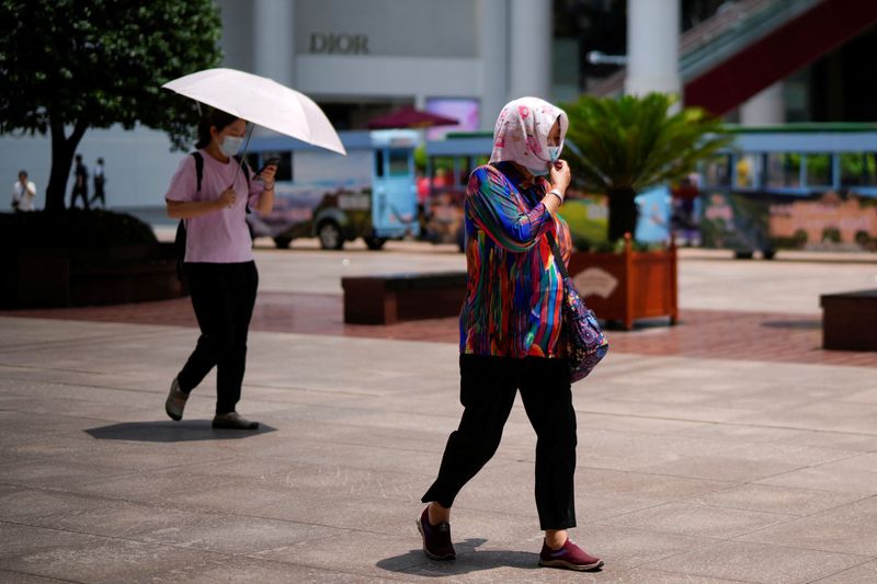 &copy; Reuters. FILE PHOTO - A woman covers herself with a towel and mask on a hot day, following a coronavirus disease (COVID-19) outbreak in Shanghai, China July 11, 2022. REUTERS/Aly Song