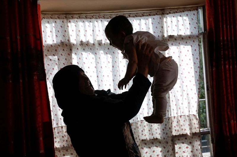 &copy; Reuters. 　８月９日、アフガニスタンのモネサ・ムバレズさんは、２０年にわたる民主政権下で獲得した女性の権利をやすやすと手放すつもりはない。写真は４日、カブールの自宅で孫をあやすグレ