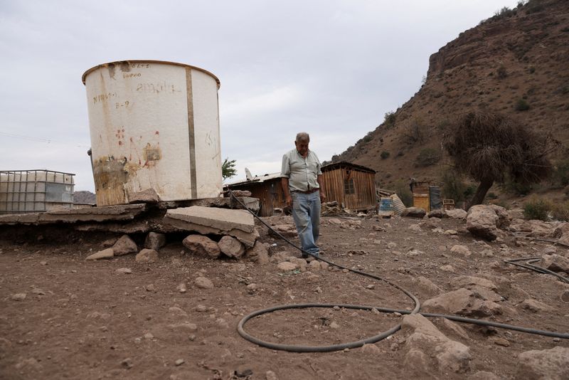 © Reuters. FILE PHOTO: Segundo Aballay, 75, a rancher, walks next to a water container used for his animals at Montenegro in Santiago, Chile April 21, 2022. 