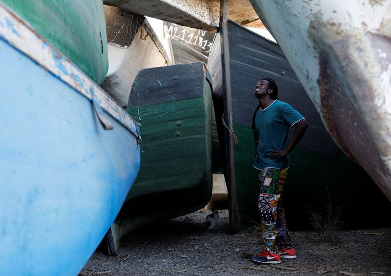 &copy; Reuters. Mohamed Fane migrant from Senegal who arrived in wooden boat to the Spanish island of Gran Canaria looks at a boat at a cemetery of abandoned wooden boats in Arinaga. Spain, August 4, 2022. REUTERS/Borja Suarez