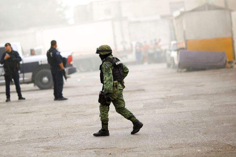 © Reuters. جندي يسير خارج متجر أحرقه مهاجمون مجهولون في هجوم بمدينة واريز الحدودية المكسيكية يوم الخميس. تصوير: جوزيه لويس جونزاليس - رويترز.