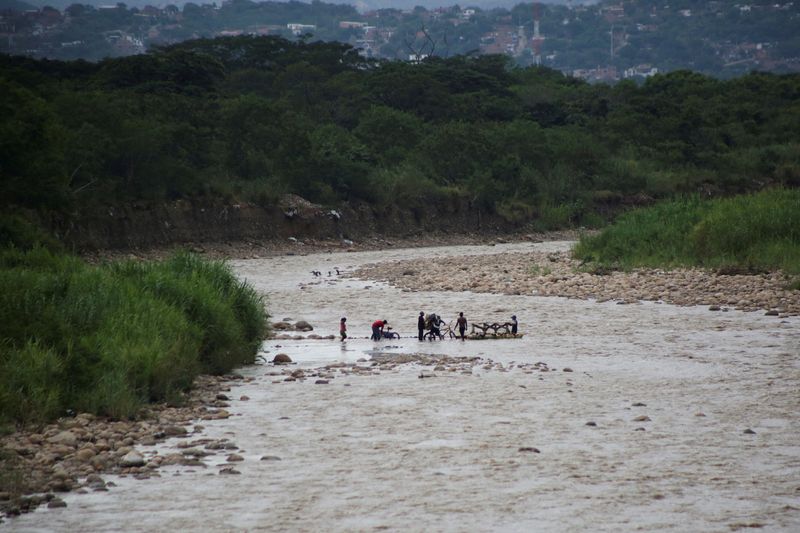 &copy; Reuters. FILE PHOTO: People cross in to Venezuela from the Colombian side through the Tachira River, as Colombia's President-elect Gustavo Petro aims to normalize relations and encourage trade with Venezuela, in Urena, Venezuela June 25, 2022. REUTERS/Carlos Eduar