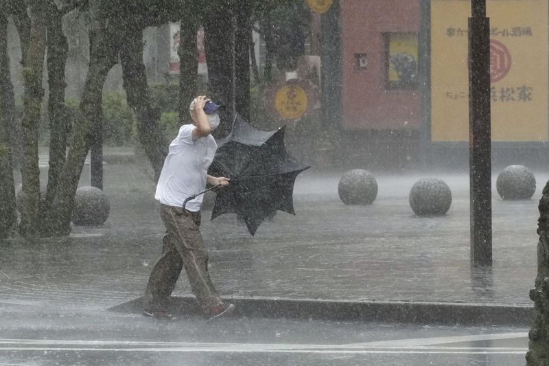 © Reuters. رجل يسير في الشارع وسط الأمطار الغزيرة التي سببتها العاصفة ميري في جزيرة هونشو يوم السبت. صورة لرويترز من  وكالة كيودو اليابانية للأنباء. (لا توجد مبيعات تجارية أو تحريرية في اليابان).