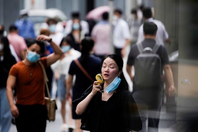 © Reuters. امرأت تستخدم مروحة صغيرة في أثناء سيرها بأحد شوارع مدينة شنغهاي الصينية في يوم حار في صورة التقطت يوم 19 يوليو تموز 2022. تصوير: ألي سونج - رويترز.
