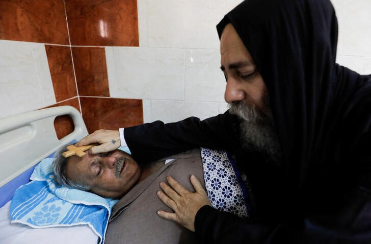 &copy; Reuters. Un sacerdote copto bendice a una víctima del incendio que afectó a la iglesia de Abu Sifin, en un hospital de Giza, Egipto. 14 agosto 2022. REUTERS/Mohamed Abd El Ghany