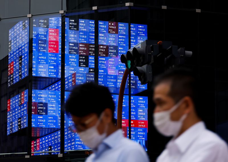 &copy; Reuters. FILE PHOTO - People pass by an electronic screen showing Japan's Nikkei share price index inside a conference hall  in Tokyo, Japan June 14, 2022. REUTERS/Issei Kato