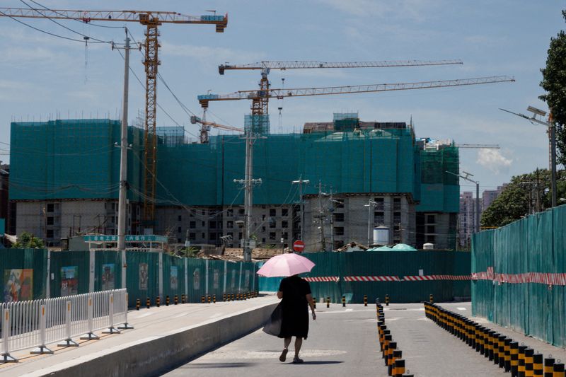 © Reuters. FILE PHOTO: A woman walks near a construction site of apartment buildings in Beijing, China, July 15, 2022. REUTERS/Thomas Peter/File Photo