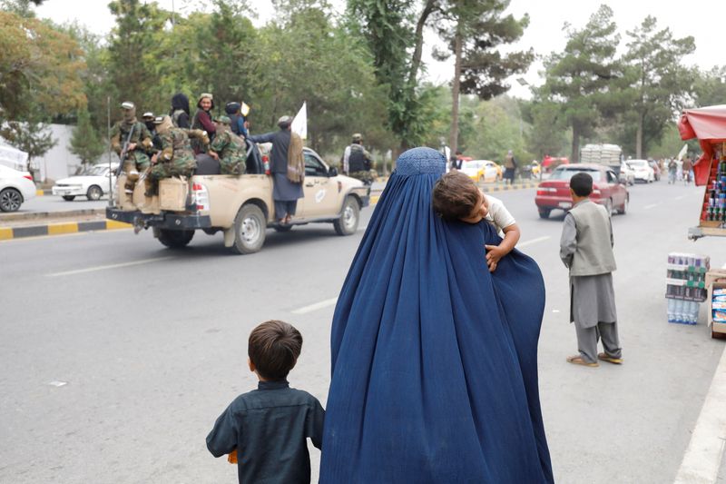 &copy; Reuters. An Afghan woman walks with her children on the anniversary of the fall of Kabul on a street in Kabul, Afghanistan, August 15, 2022. REUTERS/Ali Khara
