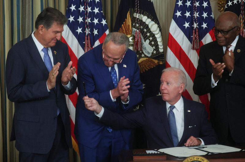 © Reuters. U.S. President Joe Biden holds out his pen to U.S. Senator Joe Manchin (D-WV) as Senate Majority Leader Chuck Schumer (D-NY) and U.S. House Majority Whip James Clyburn (D-SC) look on after Biden signed 