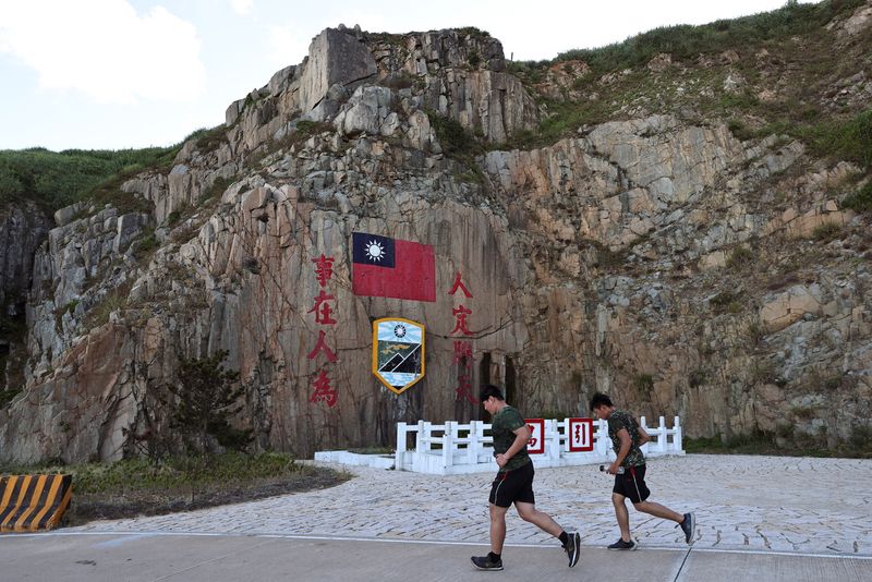 © Reuters. Soldiers march past a sign of the Taiwan flag on Dongyin island of Matsu archipelago in Taiwan August 15, 2022. REUTERS/Ann Wang