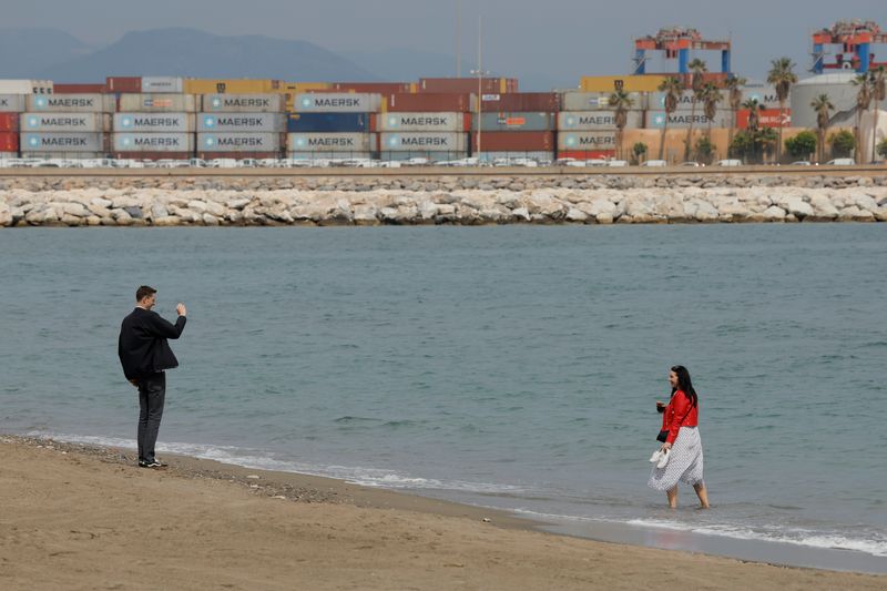 &copy; Reuters. Tourists takes pictures on a beach in front of containers in a port in Malaga, Spain, April 28, 2022. REUTERS/Jon Nazca/File Photo
