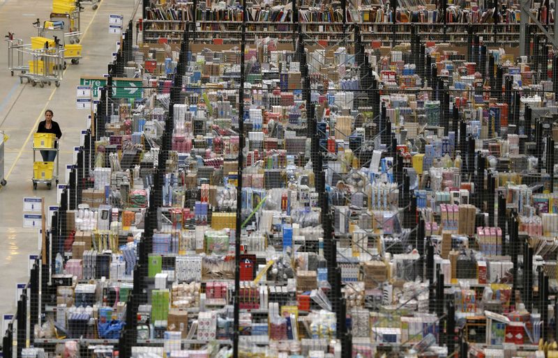 © Reuters. FILE PHOTO: A member of staff pushes a trolley as she collects orders at the Amazon fulfilment centre in Peterborough, central England November 28, 2013. REUTERS/Phil Noble