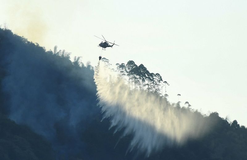 © Reuters. A helicopter works to put out wildfire in a forest, amid hot temperature in Chongqing, China August 19, 2022. cnsphoto via REUTERS 