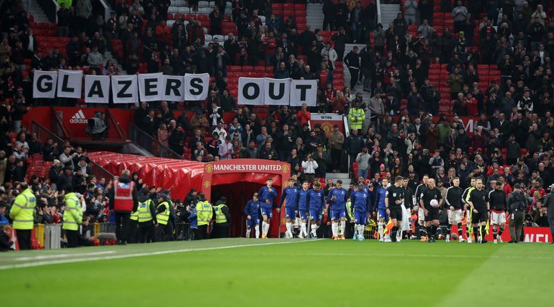 &copy; Reuters. Soccer Football - Premier League - Manchester United v Chelsea - Old Trafford, Manchester, Britain - April 28, 2022 The teams walk out as Manchester United fans display banners in protest of the Glazer family’s ownership of the club inside the stadium b