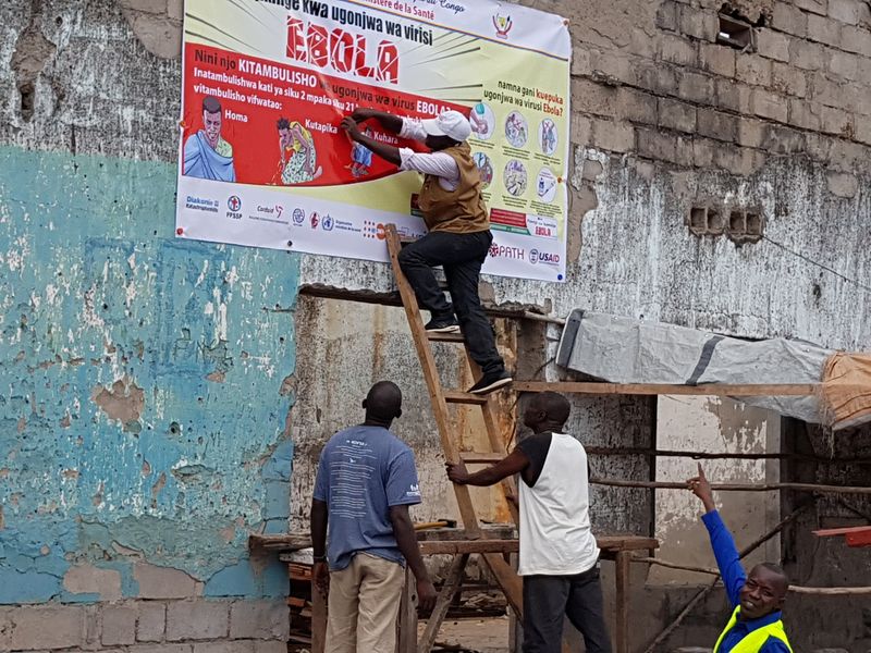 &copy; Reuters. Workers fix an Ebola awareness poster in Tchomia, Democratic Republic of Congo, to raise awareness about Ebola in the local community, on October 9, 2018.   WHO/Aboulaye Cisse/Handout via REUTERS/Files