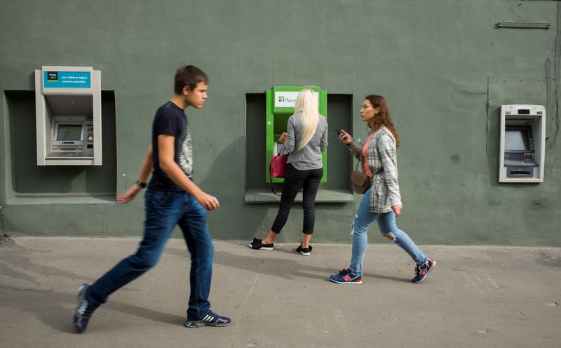 &copy; Reuters. FILE PHOTO: A woman uses an ATM machine as people walk past in central Kharkiv, Ukraine September 18, 2018. REUTERS/Gleb Garanich