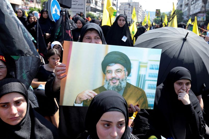&copy; Reuters. مسلمات من الطائفة الشيعية وبينهن امرأة ترفع صورة لزعيم حزب الله اللبناني حسن نصر الله خلال فعالية دينية يوم التاسع من أغسطس آب 2022 في ضواحي ب