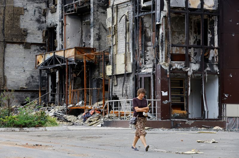 &copy; Reuters. A woman walks near a building damaged in the course of Ukraine-Russia conflict in the southern port city of Mariupol, Ukraine August 21, 2022. REUTERS/Alexander Ermochenko