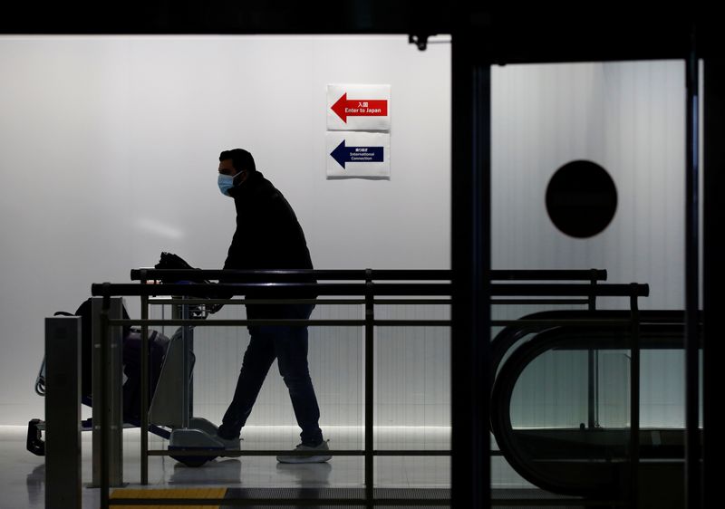 &copy; Reuters. FILE PHOTO: A passenger wearing a protective mask makes his way next to an arrival gate of Narita international airport on the first day of closed borders to prevent the spread of the new coronavirus Omicron variant amid the coronavirus disease (COVID-19)