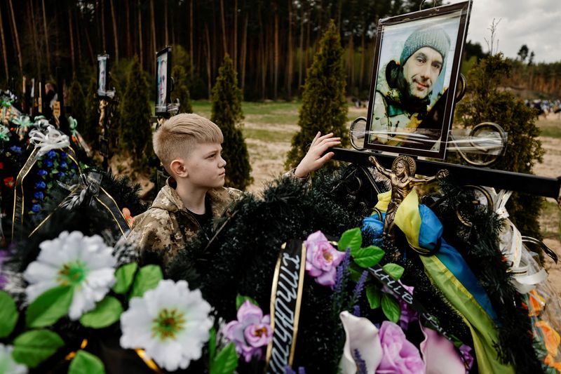 &copy; Reuters. Savelii, 10, mourns his father Ihor Krotkikh, 47, who according to his mother Alla Krotkikh, 42, was killed by shelling, as he stands by his grave during the death memorial weekend which marks a week after the Orthodox Easter, amid the Russian invasion of