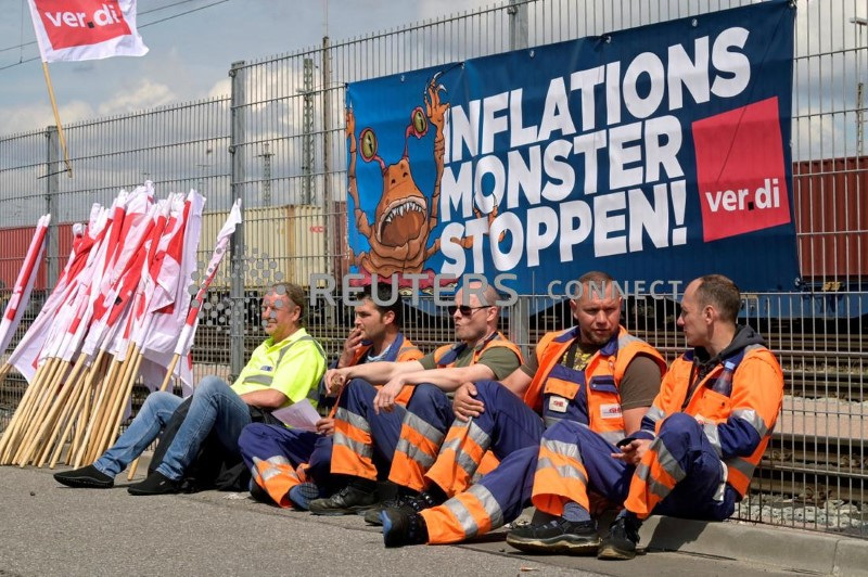 &copy; Reuters. Lavoratori seduti davanti a uno striscione che recita "Stop al mostro dell'inflazione" al Burchardkai Container Terminal mentre scioperano per ottenere salari più alti nel porto di Amburgo, Germania, 9 giugno 2022. REUTERS/Fabian Bimmer/Foto d'archivio