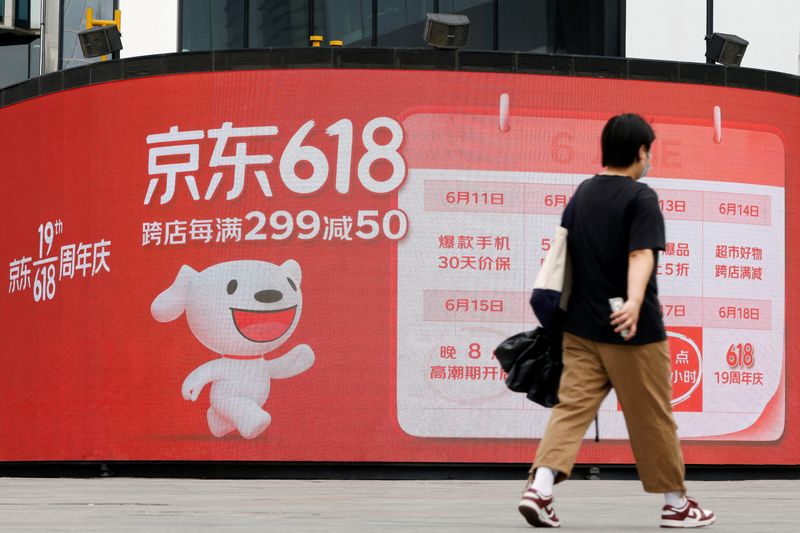 &copy; Reuters. FILE PHOTO: A resident, wearing a face mask following the coronavirus disease (COVID-19) outbreak, walks past a JD.com advertisement for the "618" shopping festival displayed outside a shopping mall in Beijing, China June 14, 2022. REUTERS/Carlos Garcia R