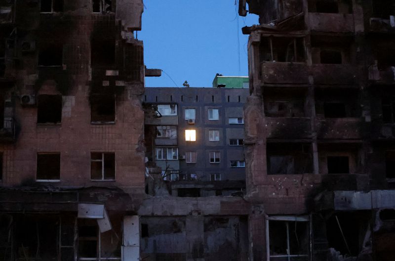 &copy; Reuters. Imagen de archivo de luz emanando de una ventana de un bloque de departamentos detrás de un edificio residencial dañado durante el conflicto entre Ucrania y Rusia en la sureaña ciudad portuaria de Mariúpol, Ucrania. 16 de julio, 2022. REUTERS/Alexande