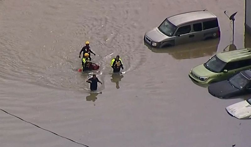 © Reuters. Rescue personnel wade through floodwaters after heavy flooding in the Dallas metro area submerged roads and entire neighborhoods, in Dallas County, Texas, U.S., August 22, 2022, in this still image taken from video. WFAA TV via ABC via REUTERS 