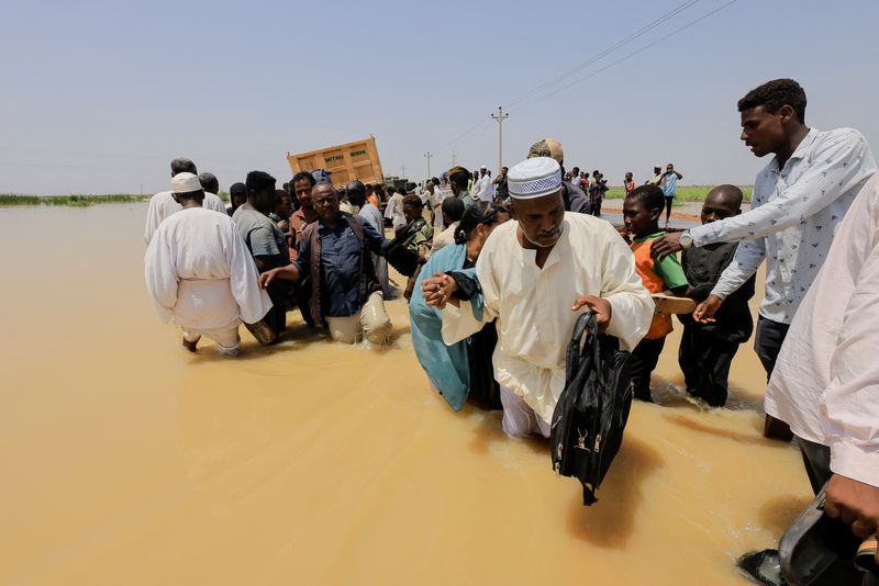 &copy; Reuters. مواطنون يخوضون في مياه السيول في مدينة المناقل بولاية الجزيرة يوم الثلاثاء. تصوير محمد نور الدين عبد الله - رويترز.