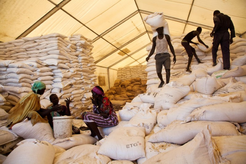 &copy; Reuters. IMAGEN DE ARCHIVO. Los hombres llevan bolsas de alimentos mientras las mujeres esperan sus raciones en el sitio de distribución de alimentos del Programa Mundial de Alimentos (PMA) de las Naciones Unidas en Pibor, Sudán del Sur. REUTERS/Adriane Ohanesia