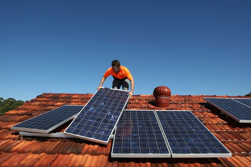 &copy; Reuters. FILE PHOTO: Solar system installer Thomas Bywater adjusts new solar panels on the roof of a house in Sydney August 19, 2009.  REUTERS/Tim Wimborne/File Photo
