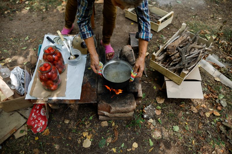 &copy; Reuters. A woman cooks a meal on wood fire in Niu-York (New York) near Toretsk, war-affected area in eastern Ukraine, as Russia's attack in Ukraine continues, Donetsk region, Ukraine August 25, 2022. REUTERS/Ammar Awad
