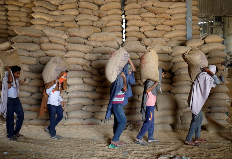 &copy; Reuters. FILE PHOTO: Workers carry sacks of wheat for sifting at a grain mill on the outskirts of Ahmedabad, India, May 16, 2022. REUTERS/Amit Dave