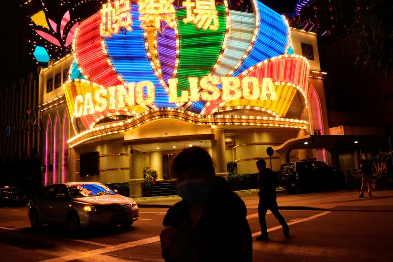 &copy; Reuters. FILE PHOTO: People wearing masks walk in front of Casino Lisboa, before its temporary closing, following the coronavirus outbreak in Macau, China February 4, 2020. REUTERS/Tyrone Siu/File Photo