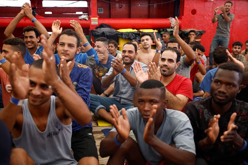 &copy; Reuters. مهاجرون يحتفلون بالسماح لهم بالنزول في ميناء ميسينا الإيطالي يوم الجمعة. تصوير: خوان مدينا - رويترز. 